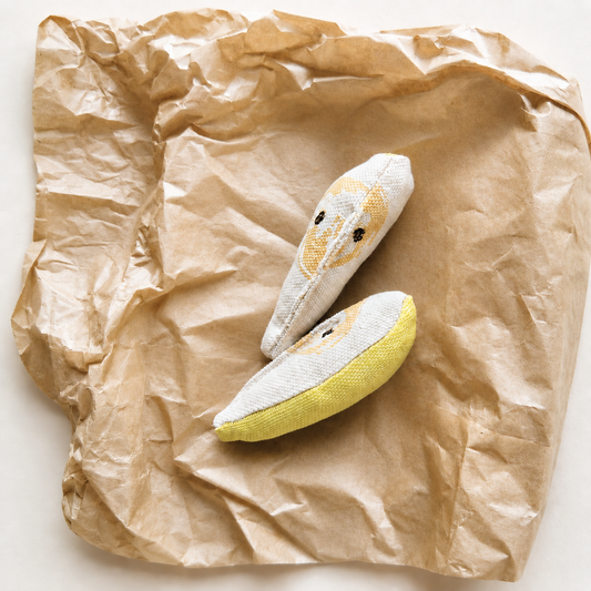Handmade fabric banana slices displayed on crumpled kraft paper in a bright minimal product photo.