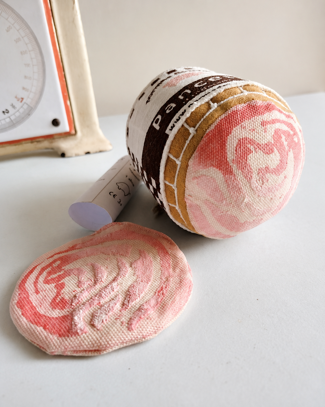 Handmade pancetta soft play food set with rolled pancetta and fabric slice on a light studio surface.