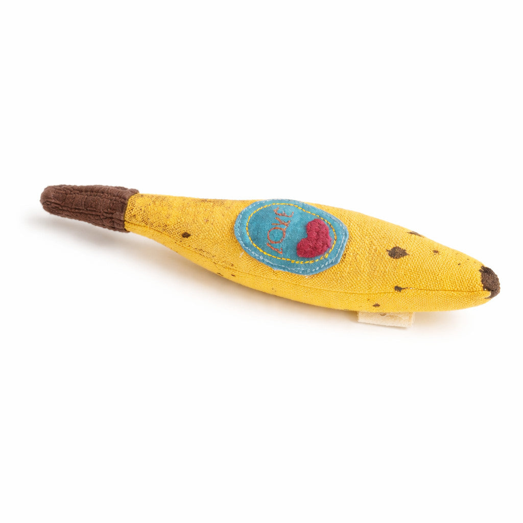 Yellow toy resembling a fabric banana with a blue patch and red heart on a white background