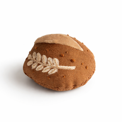 Handmade fabric bread roll toy with embroidered wheat detail on a white studio background