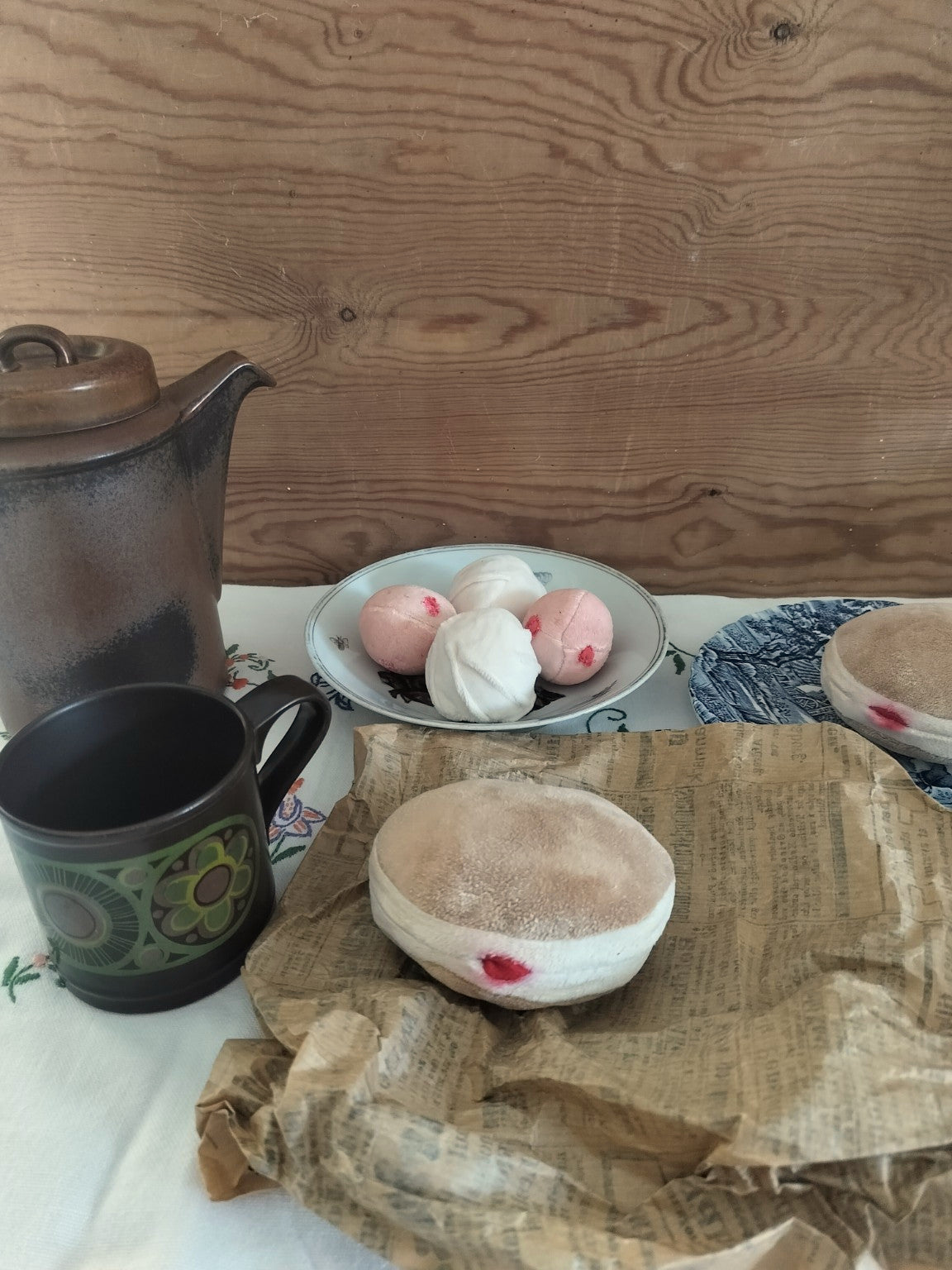 Handmade fabric Berliner on vintage paper, styled with a ceramic cup, teapot and other play pastries.