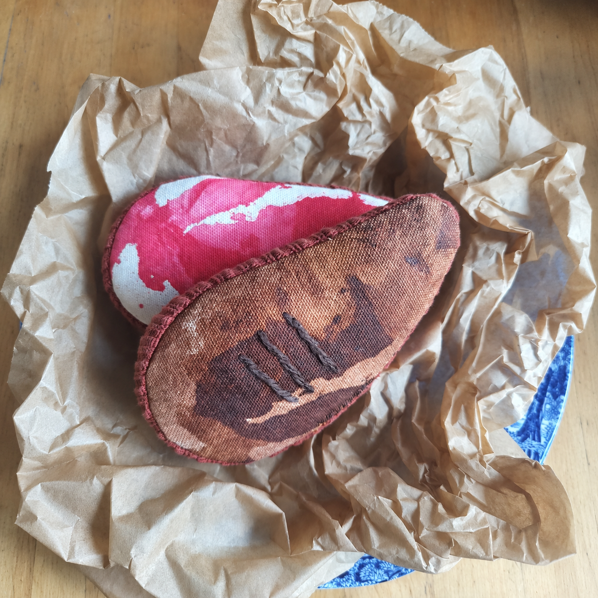 Two handmade fabric ribeye steaks by normadot, showing raw and grilled sides. Made with partly upcycled fabrics and displayed on crumpled kraft paper.