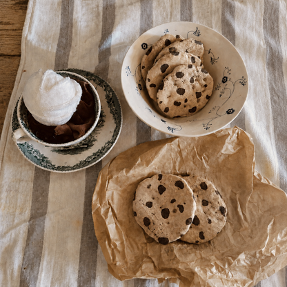 Handmade fabric chocolate chip cookies arranged for pretend tea party play with a vintage cup and plates.