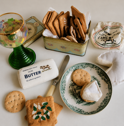 Handmade fabric whole wheat crackers with soft textile camembert cheese and butter, styled as pretend play food for play kitchens.